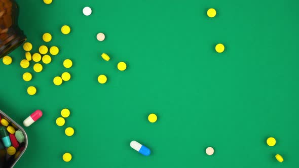 Medicines spilling on green paper for medical background concept top view with copy space