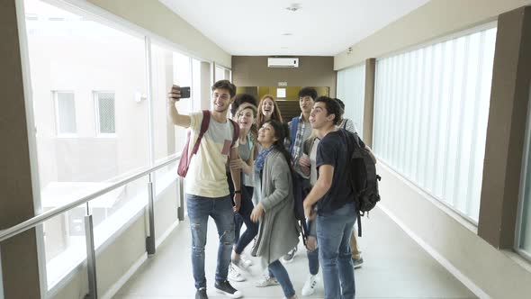 Group of students taking selfie with smartphone in corridor