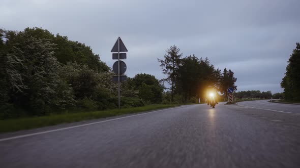 Long Road With a Person Riding a Motorcycle on a Gray Concrete Road alt