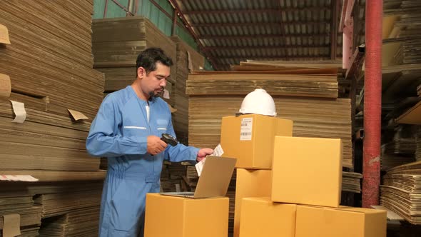 Asian male worker scan bar codes to check orders at parcels warehouse factory. alt