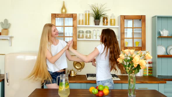 Two Joyful Girls Dancing And Shaking Long Hair In The Kitchen