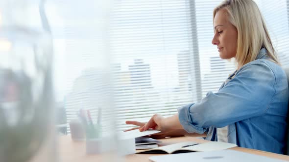 Businesswoman opening laptop at her desk alt