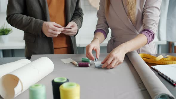 Closeup of Girl and Guy Tailors Choosing Fabric and Threads for New Garments alt