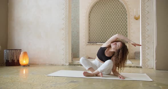 Sporty CurlyHaired Woman Does Yoga Stretching Exercises