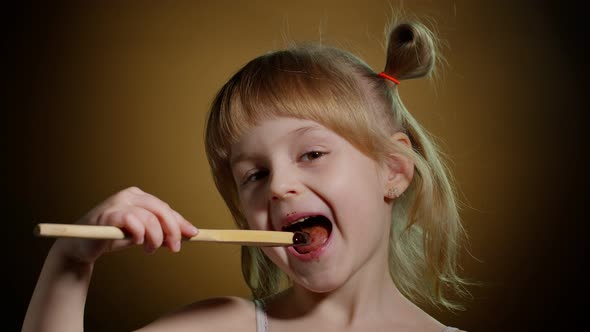 Joyful Smiling Child Kid Girl with Dirty Face From Melted Chocolate on Dark Background in Studio alt