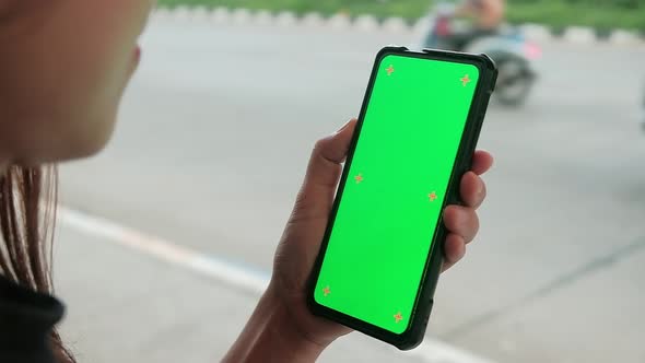 Asian woman using mobile phone with green mock-up screen chroma key alt