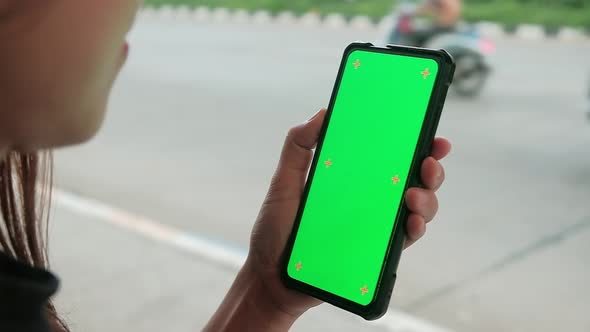 Asian woman using mobile phone with green mock-up screen chroma key