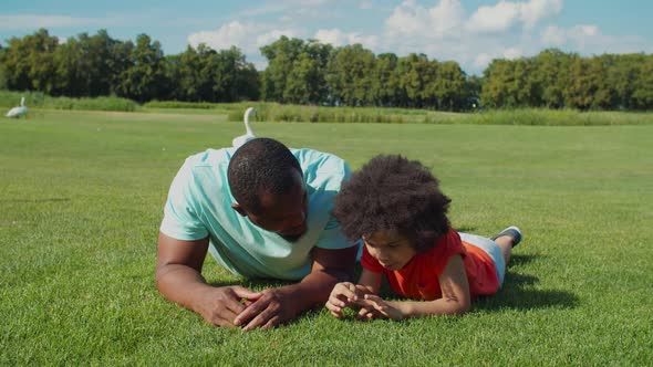African Father with Cute Son Bonding on Park Lawn alt