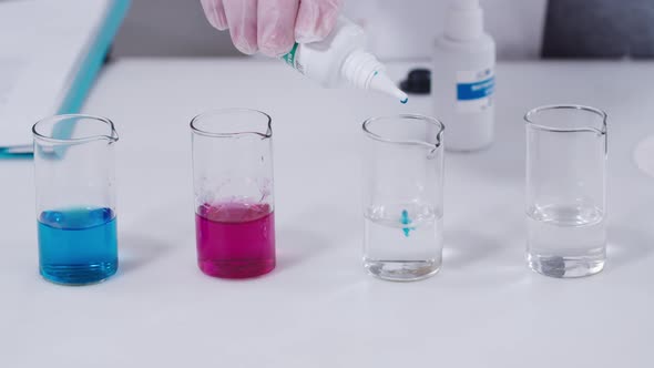 Laboratory Technician Hand is Holding a Plastic Container and Adding Some Colored Substance to the