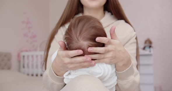 A Young Mother Is Holding Her Newborn Baby On Her Lap. Maternal Care