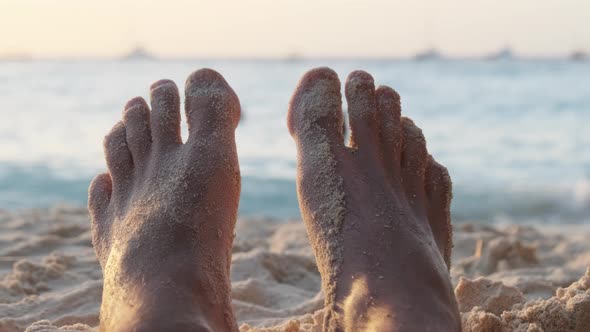 POV Feet of Young Man Lying on Sandy Beach By the Ocean During Sunset Zanzibar alt
