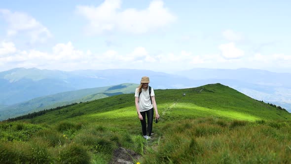 Female Tourist with a Travel Backpack Climbs a Mountain Stone Path High in the Carpathian Hills