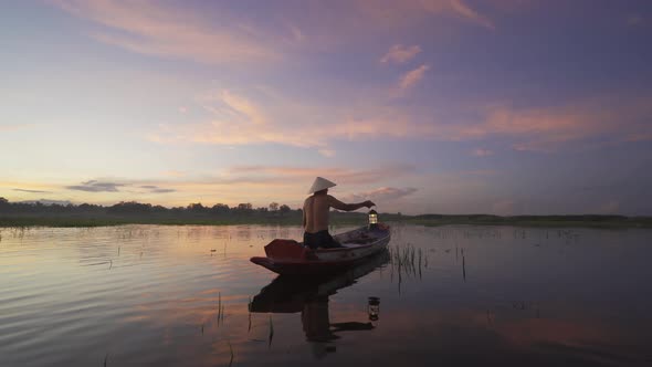 Silhouette Fisherman casting or throwing a net for catching freshwater fish in nature lake