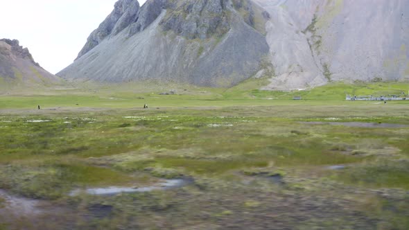 People Near Bogs And Green Meadows In Viking Village, Mount Vestrahorn, Iceland. Aerial alt