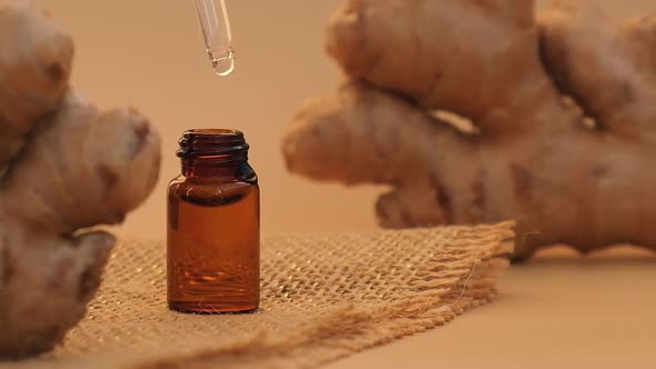 Glass Pipette of Essential Ginger Oil Dripping Ginger Root on Beige Background alt