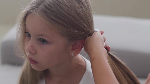 Mom Makes Her Little Daughter Hair Tying Her Hair in a Ponytail