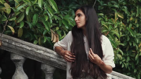 Alone Arabian Woman Is Standing in a Tropical Garden and Touching Her Long Hair alt