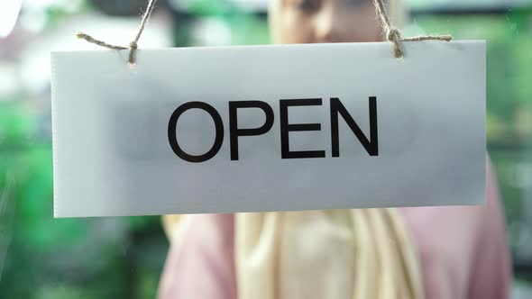 young cafe owner turning storefront sign from close to open and welcoming customers at cafe. alt