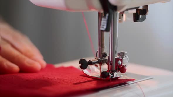 Hands of Woman Tailor Sew Straight Seam on Red Clothing on Sewing Machine