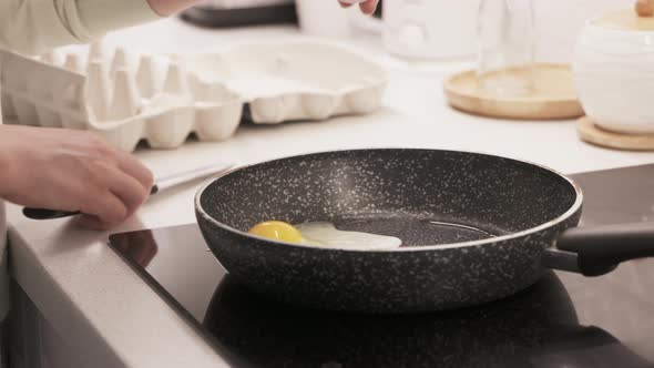 Woman Cooking Scrambled Eggs on Electric Stove Top in the Kitchen Frying Pan with Fried Eggs on alt