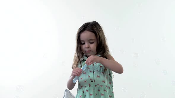 Cute young girl playing with soap bubbles. Portrait. White background