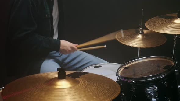 Drummer Playing the Drum Set in a Dark Room on a Black Background alt