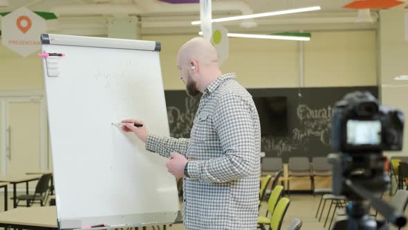 Teacher Records Video Lessons He Stands and Writes with a Pen on a Flip Chart alt