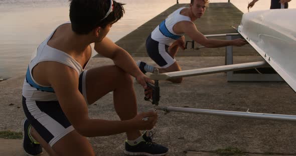 Male rowers preparing the boat before practice alt