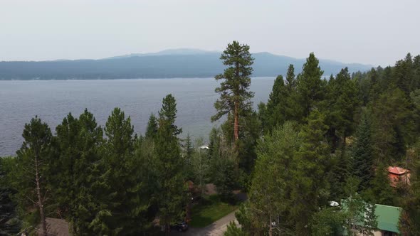 Drone shot revealing Payette Lake through the pine trees on a smoky day in McCall, Idaho. This cinem alt