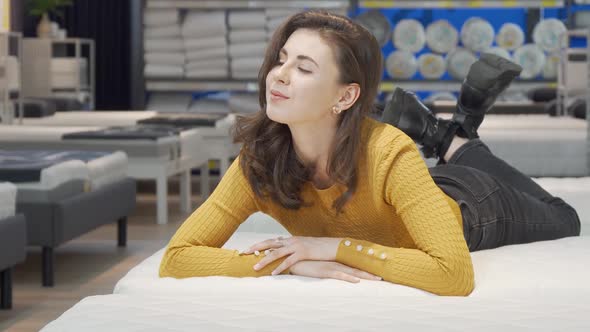 Lovely Woman Trying Orthopedic Mattress at Furnishings Store