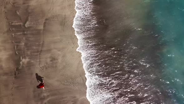 Top View of a Woman in Red Dress Walking Barefoot Along Wet Sand Ocean Beach alt