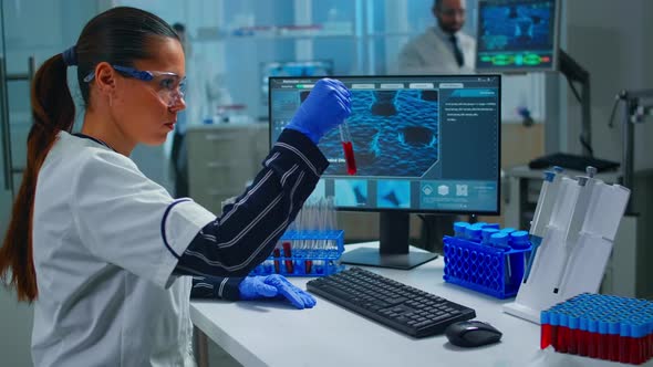 Woman Technologist Doing a Laboratory Test Examining a Flask with Blood Sample alt