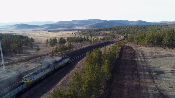 Railway Cargo Cars Carrying Coal Through Forests and Hills