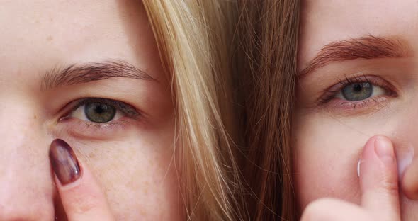 close-up portrait of the face of two fair-haired women smear cream on their cheeks with their finger alt