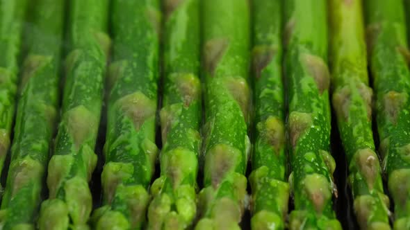 cooking green asparagus on grill pan, close up. Sliding shot. 4K UHD video alt