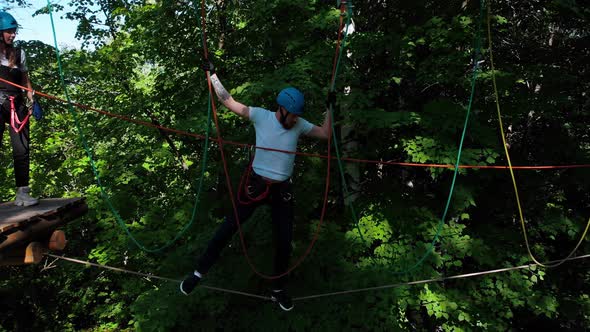 Extreme Rope Adventure in the Park - Man and Woman Walking on the Rope Between Two Stand with an alt