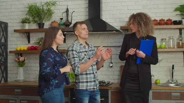 Confident Pretty Female Realtor Showing View From Window of New House to Couple alt