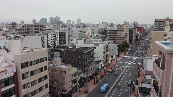 Tokyo city skyline and traffic on a cloudy grey day. Pan shot from high up. alt