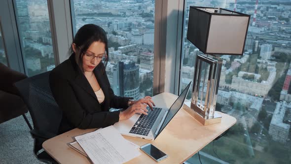Portrait of Business Woman with Glasses in the Office. Girl Sitting at the Table and Working on a alt
