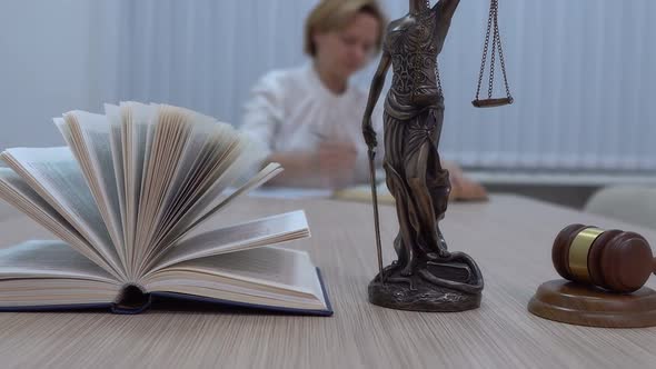 a Lawyer in the Workplace Examines Documents and Legislation the Statuette of Themis with a Master alt