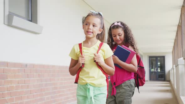 Video of happy diverse girls walking at school corridor alt