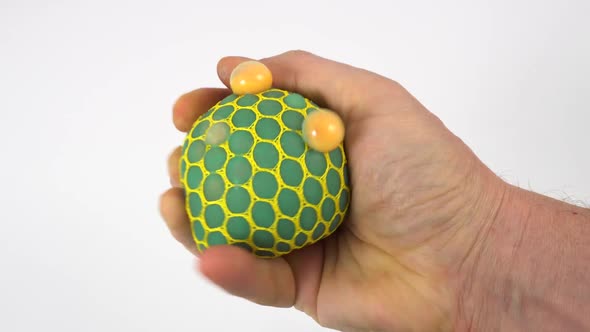 Man's hand squeezing stress ball on white. Squeezing green anti stress toy. 