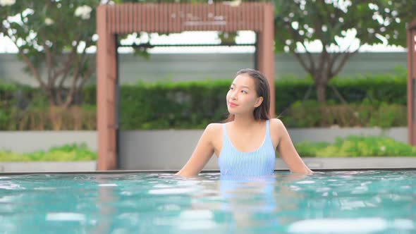 Young asian woman enjoy around outdoor swimming pool for leisure alt