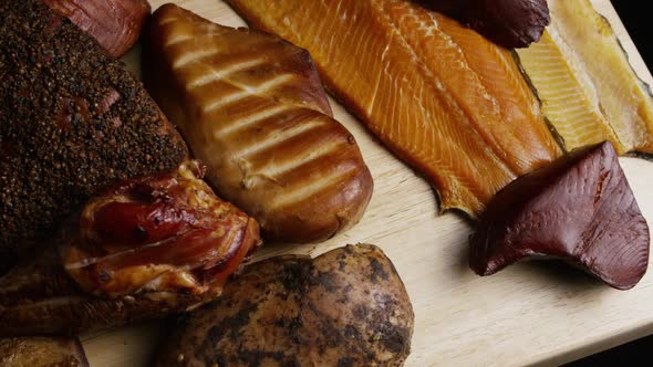Rotating shot of a variety of delicious, premium smoked meats on a wooden cutting board  alt