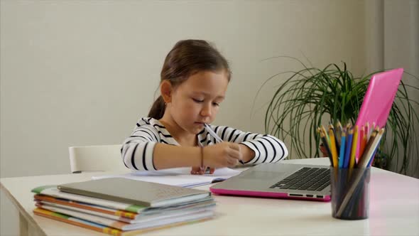 Little Child Girl is Studying Online at Home