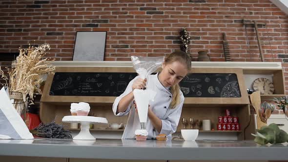 Young Confectioner Putting Cream on the Cake Using Pastry Bag alt