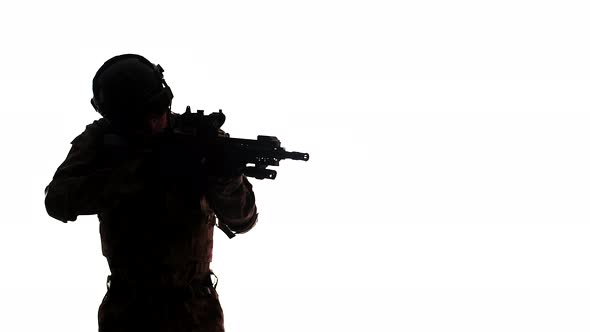 Man in an Army Uniform and Helmet Takes Aim with a Rifle Removes Weapon While Standing in the Studio alt