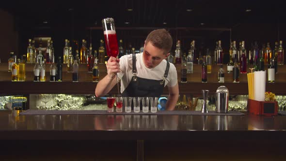 Bartender Pours Alcohol in Shot Glasses One By One