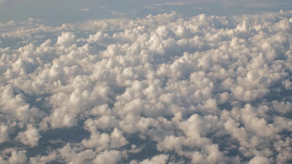 Fluffy Clouds From Above While Flying in Airplane alt