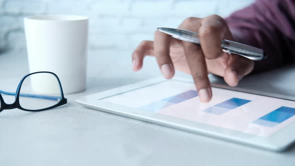 Man's Hand Working on Digital Tablet at Office Desk, Using Self Created Chart  alt